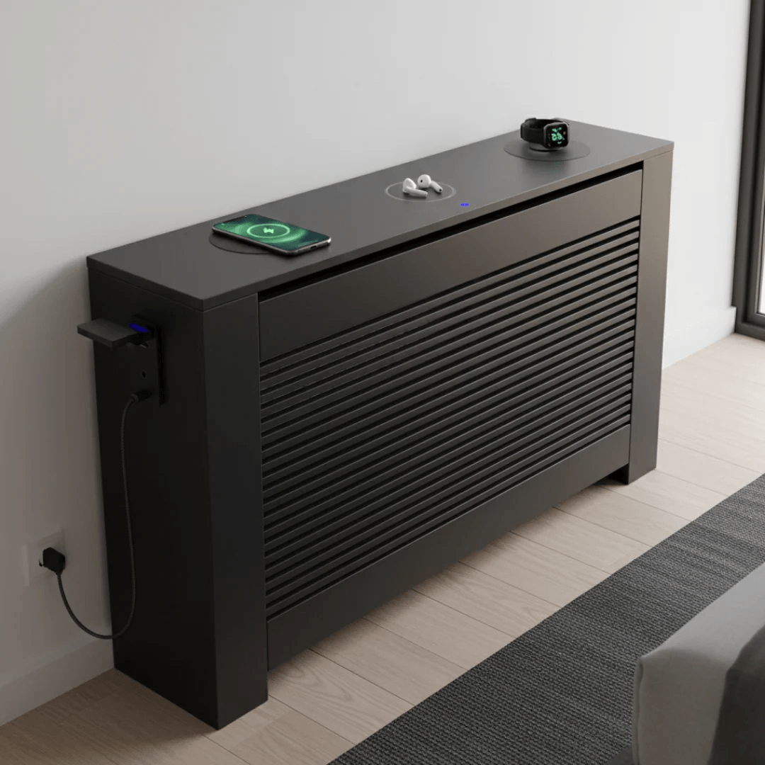 Modern black radiator cover with electronic devices on top in a room setting.